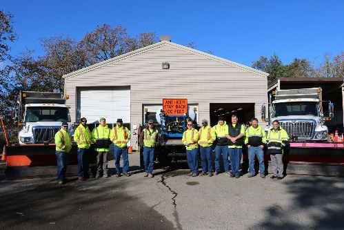Public Works posing in front of snow plows. 